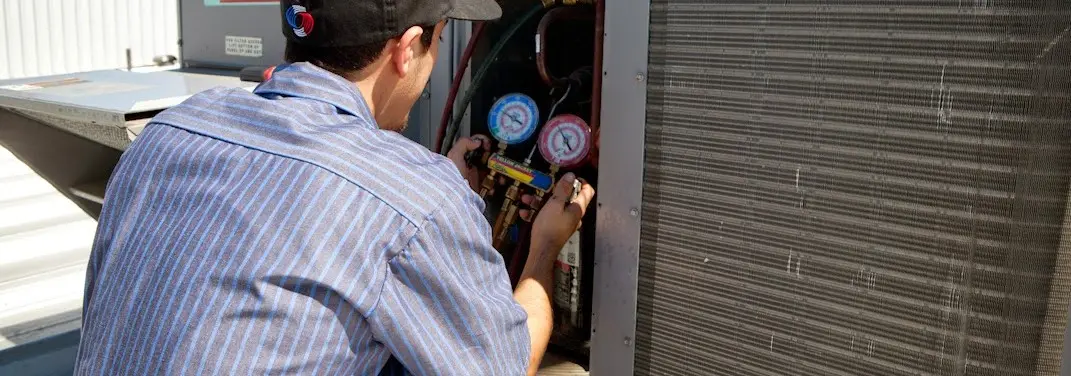 HVAC technician servicing a condenser unit in Vestal